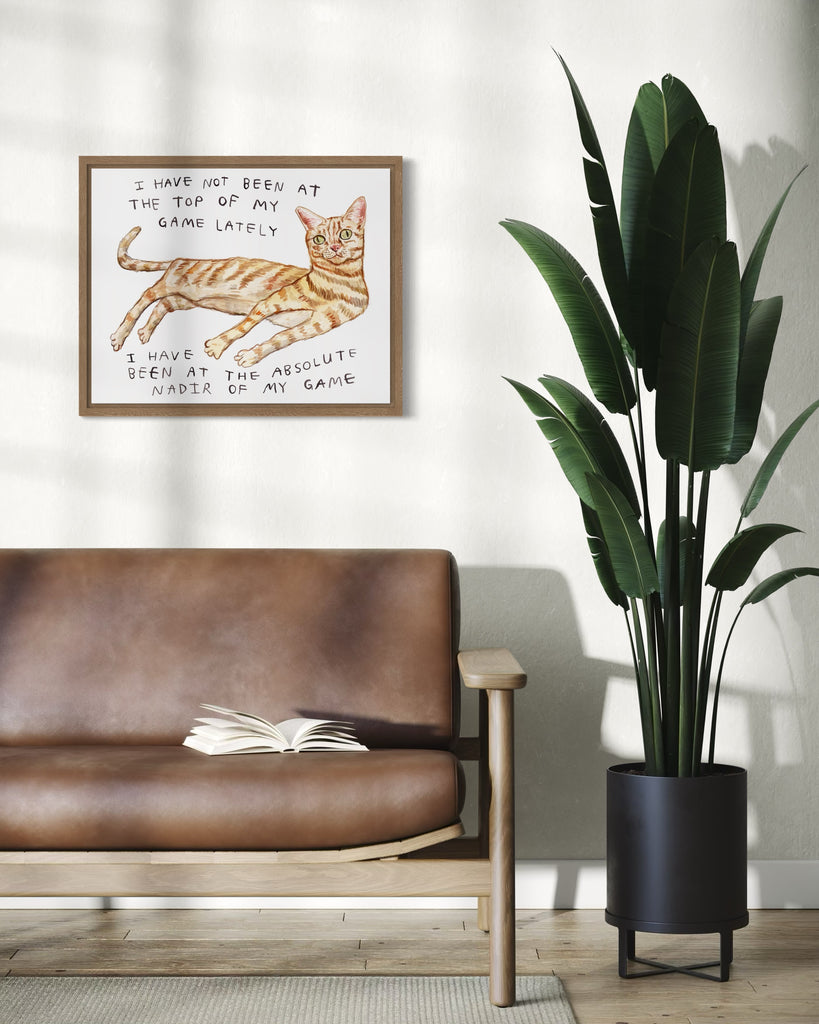 A living room with a tall plant, a leather couch, and a painting of an orange cat. The orange cat is painted in watercolour by Heather Buchanan, and it is wonky and walleyed, with text that reads: I have not been at the top of my game lately, no, i have been at the absolute nadir of my game.